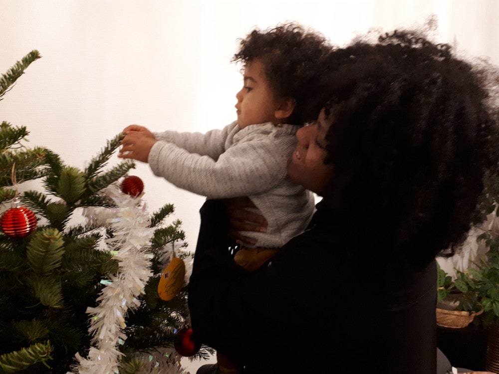 Edna aide Adao à accrocher une boule sur le sapin